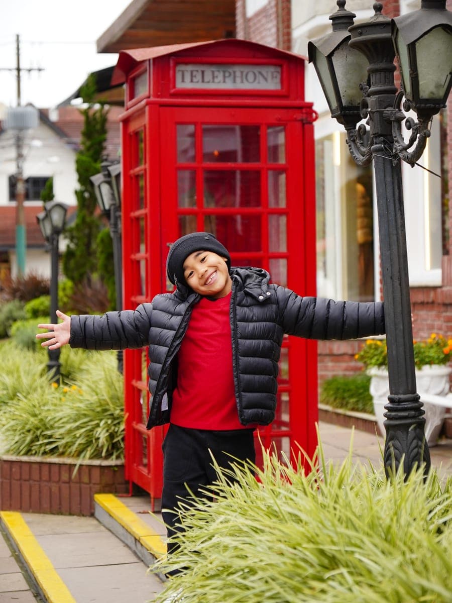 Menino em frente à cabine telefônica europeia do centro de Gramado