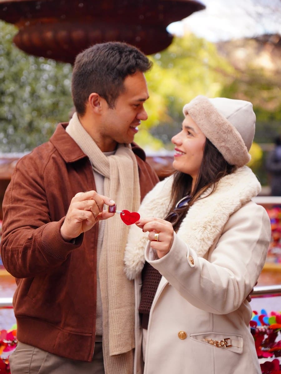 Casal sorrindo em frente à fonte do amor no centro de Gramado